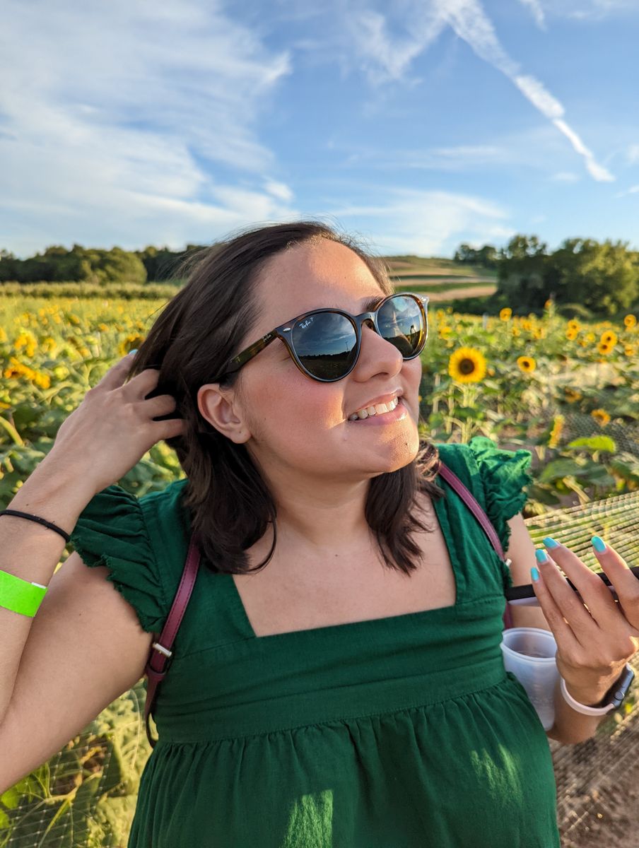 Woman in sunglasses and a green dress in a sunflower field