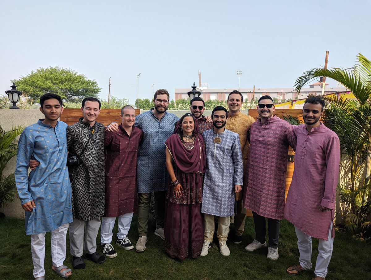 Nine people in colorful kurtas on a lawn