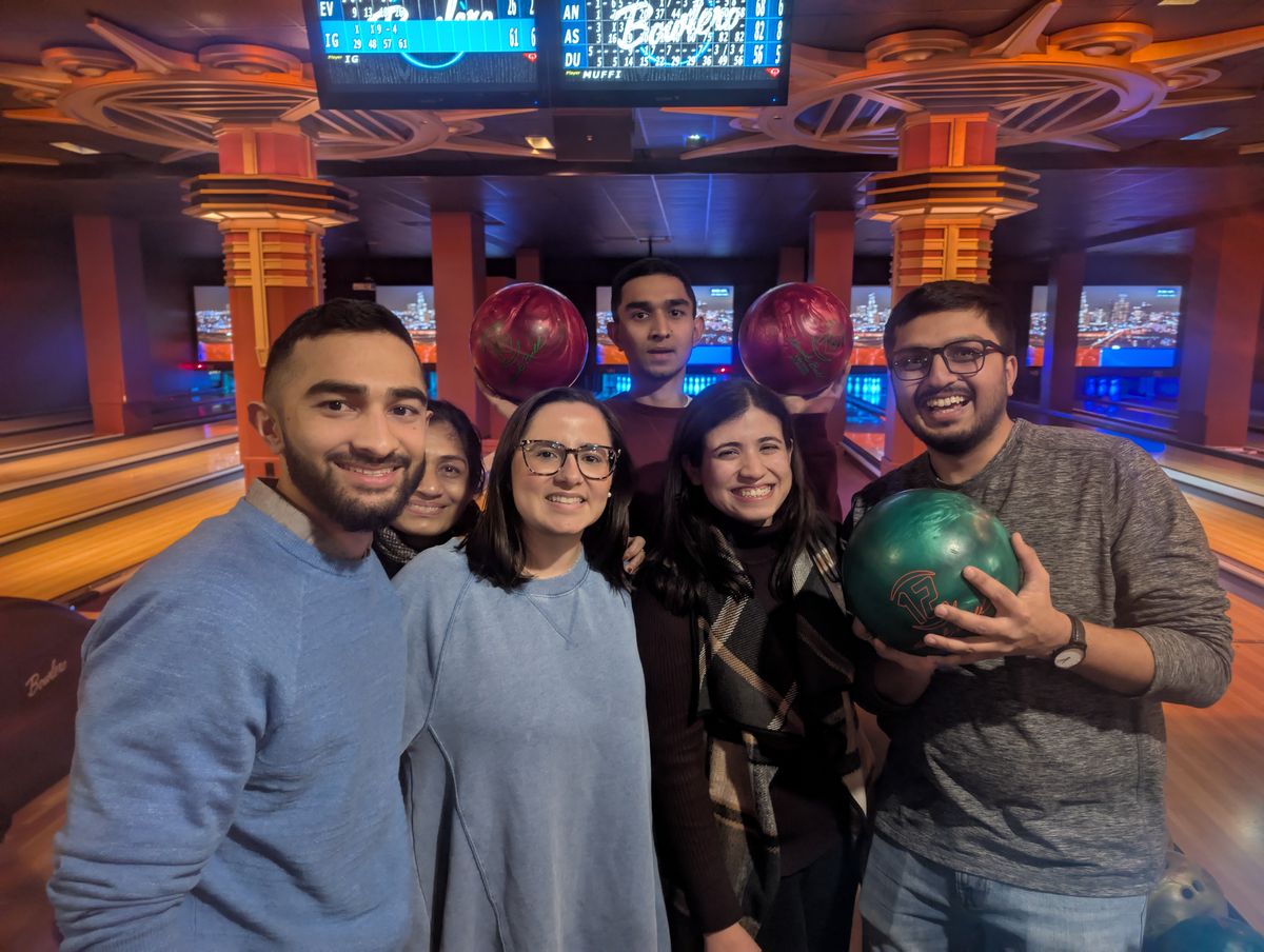 Six friends holding bowling balls at a bowling alley